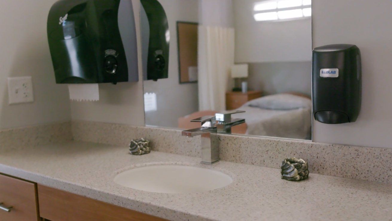A bathroom with a sink and a toilet paper dispenser