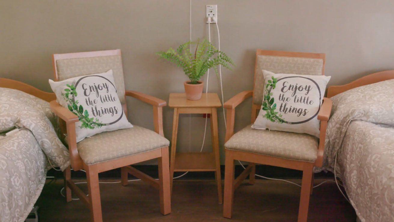 Two chairs with pillows on them are sitting next to two beds in a room.