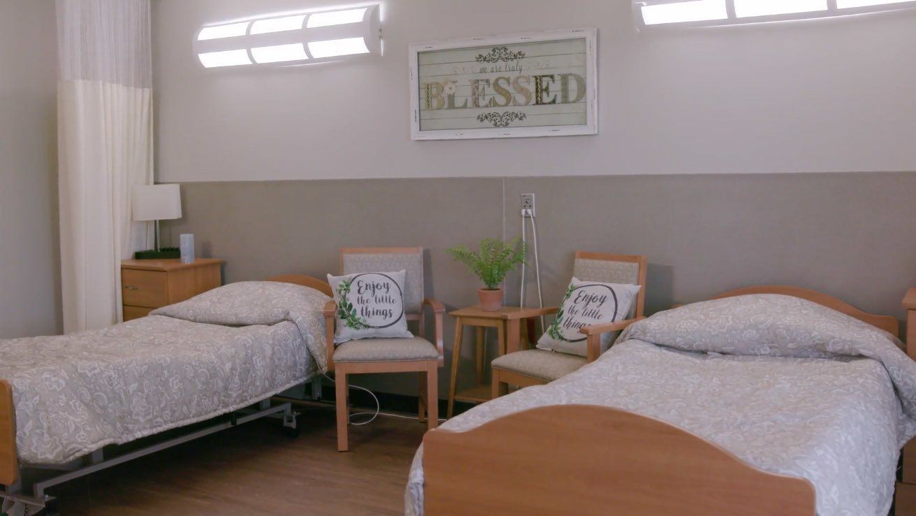 A hospital room with two beds and a sign on the wall that says blessed.