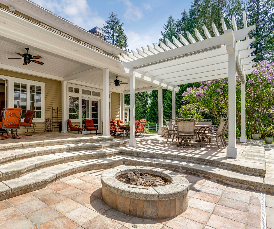 A stone patio with a pergola, fire pit and tables and chairs at a Vermont home