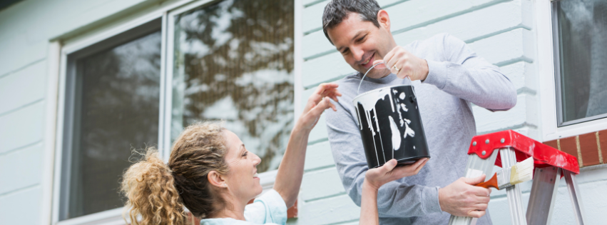 Two homeowners apply a fresh coat of white paint to their Vermont home