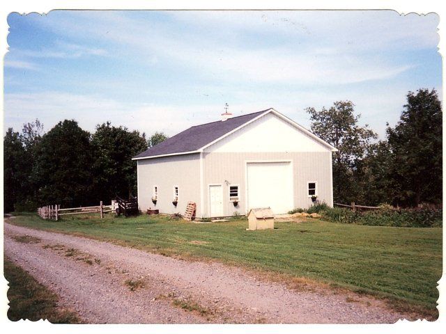 A white barn sits in the middle of a grassy field