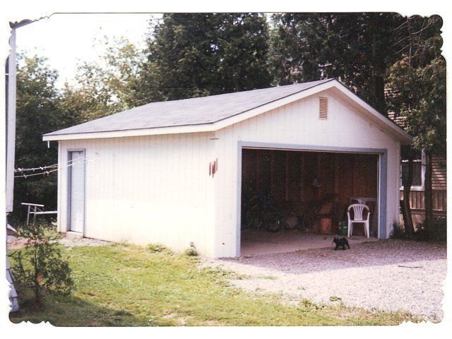 A white garage with the door open and a dog standing in front of it