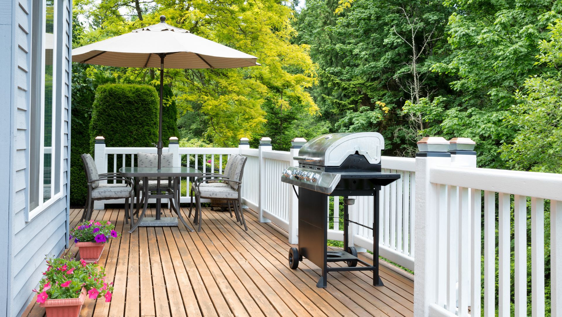 A grill on the deck with a table and chairs.