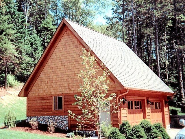 A wooden house with a white roof is surrounded by trees