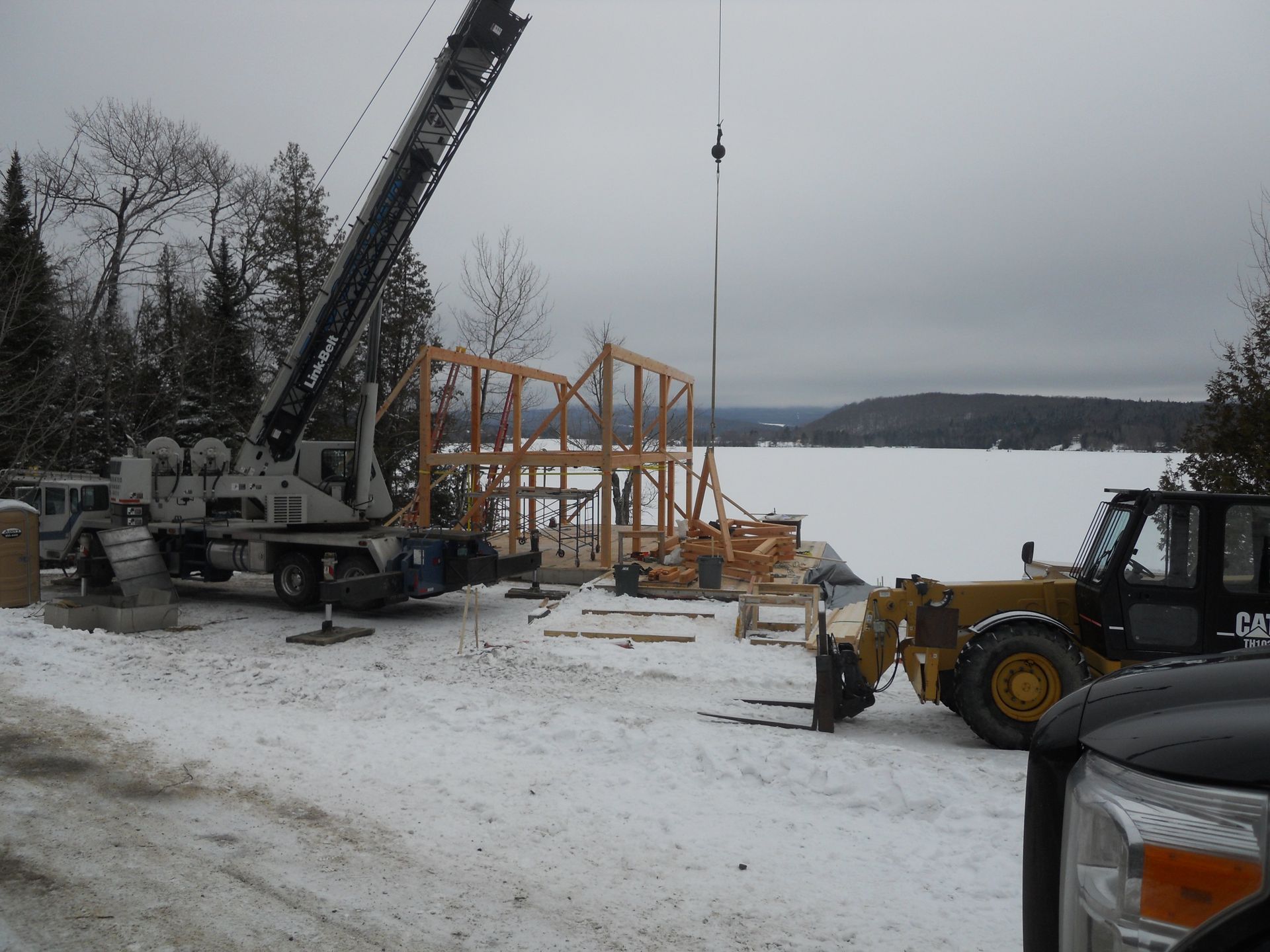 A construction site with a crane and a forklift in the snow