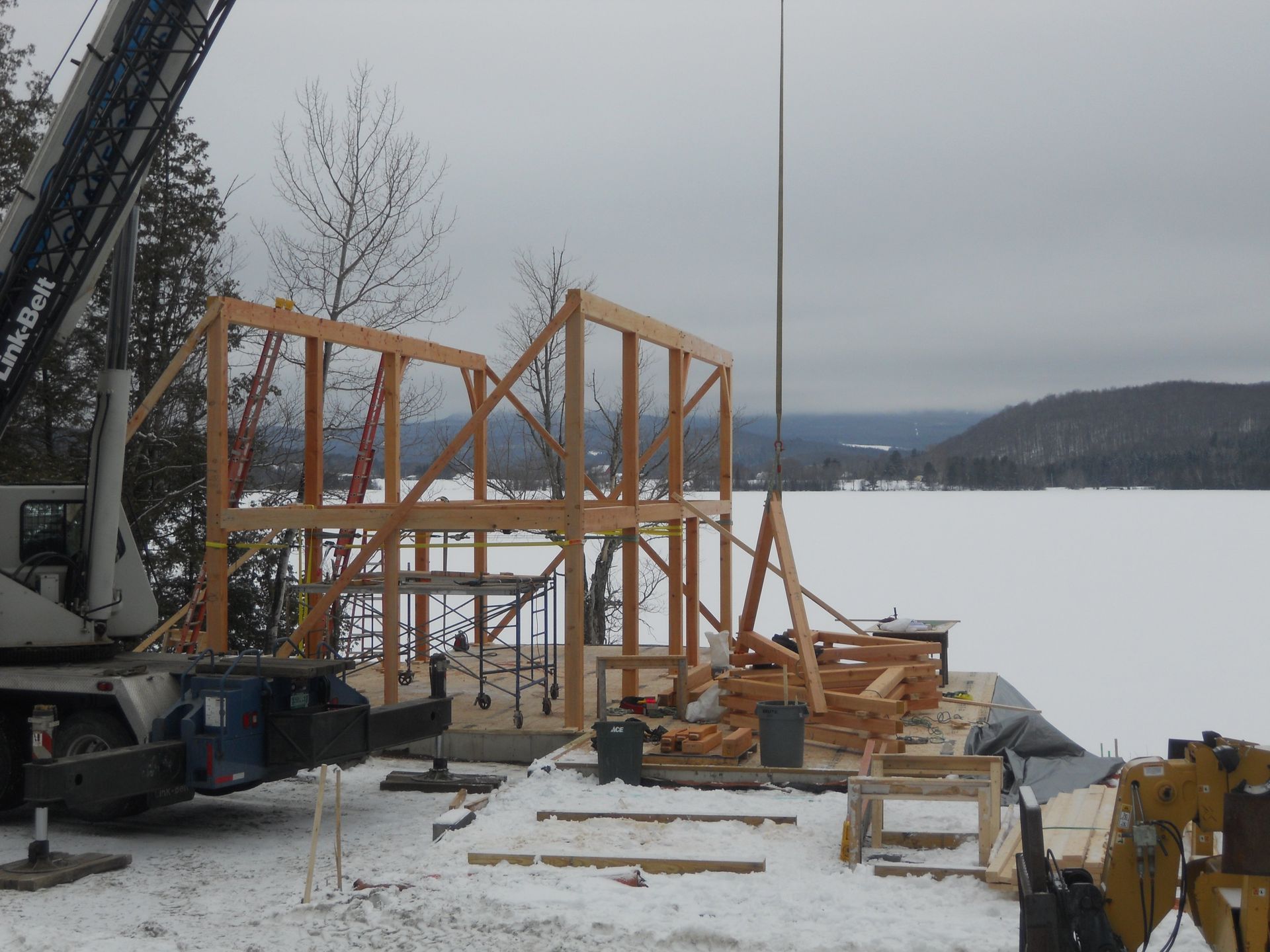 A crane is lifting a wooden structure in the snow