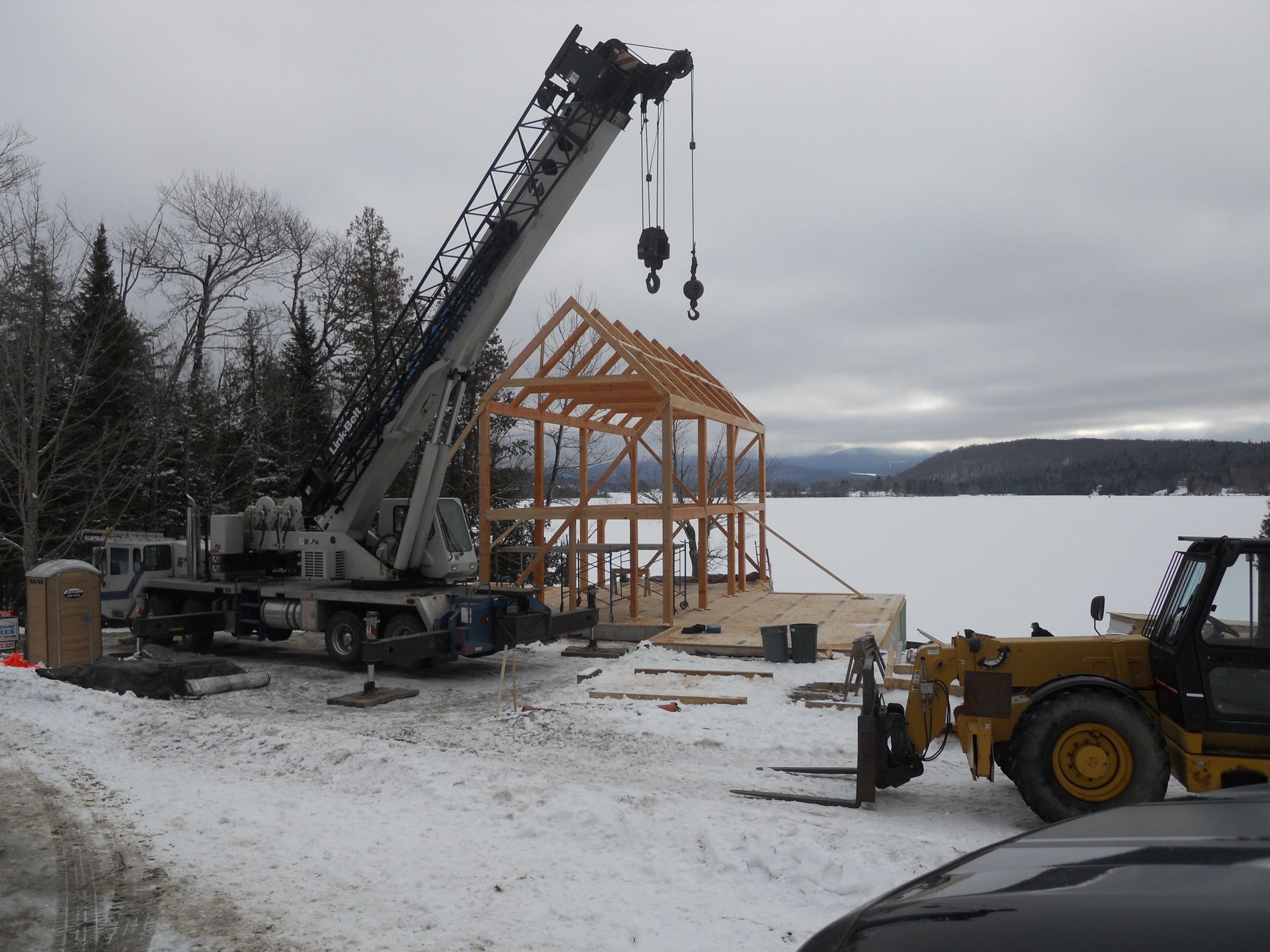 A crane is lifting a wooden structure in the snow