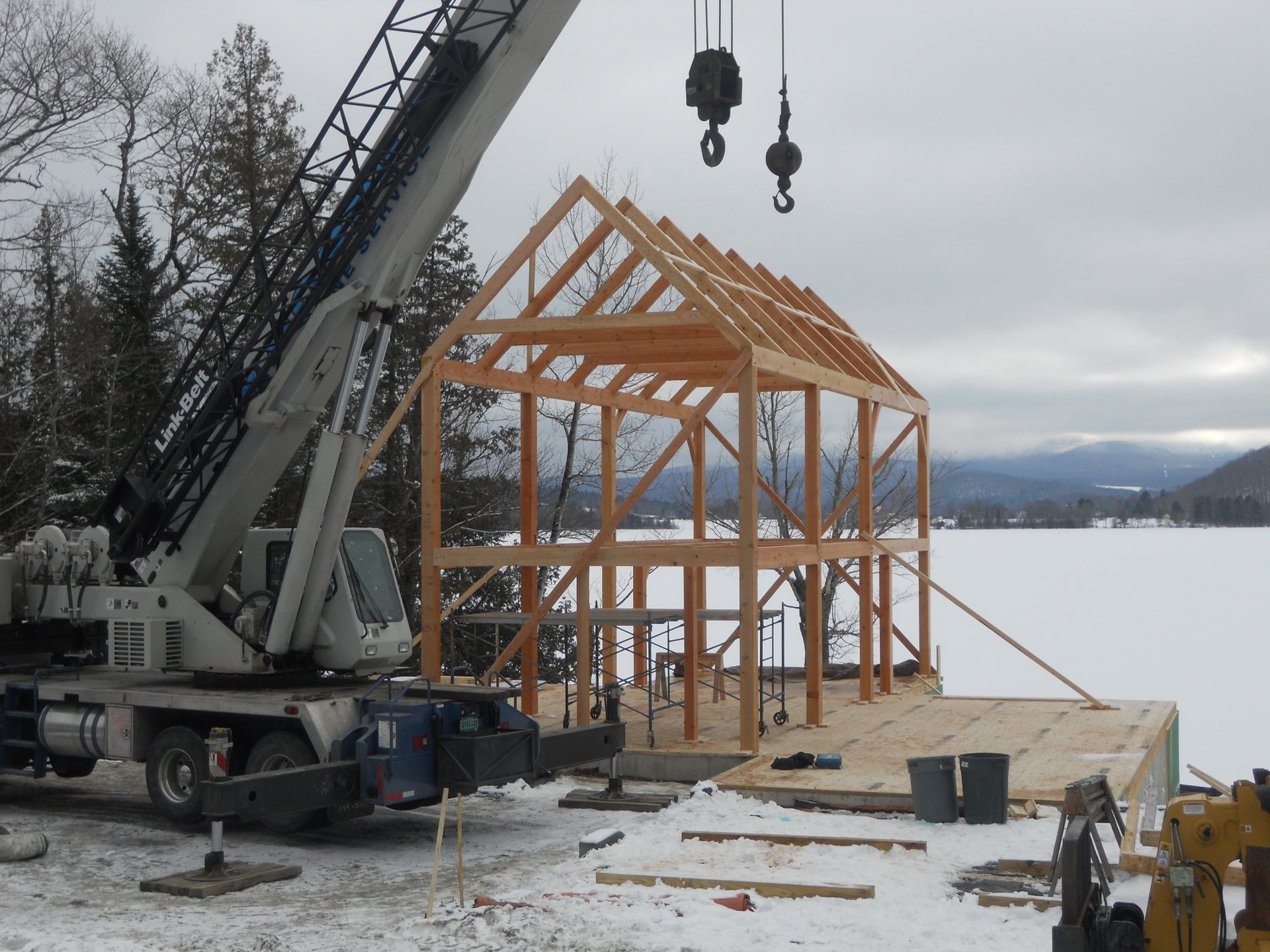 A crane is lifting a wooden structure in the snow