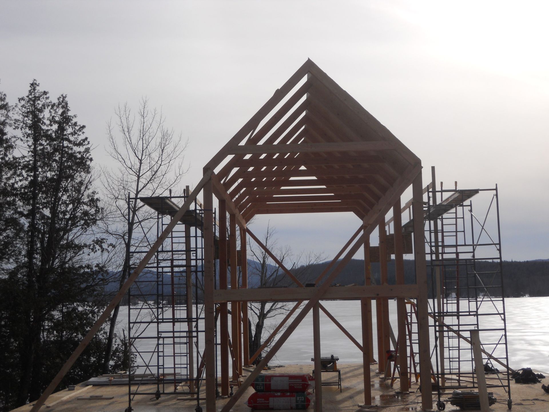 A large wooden structure is being built next to a body of water
