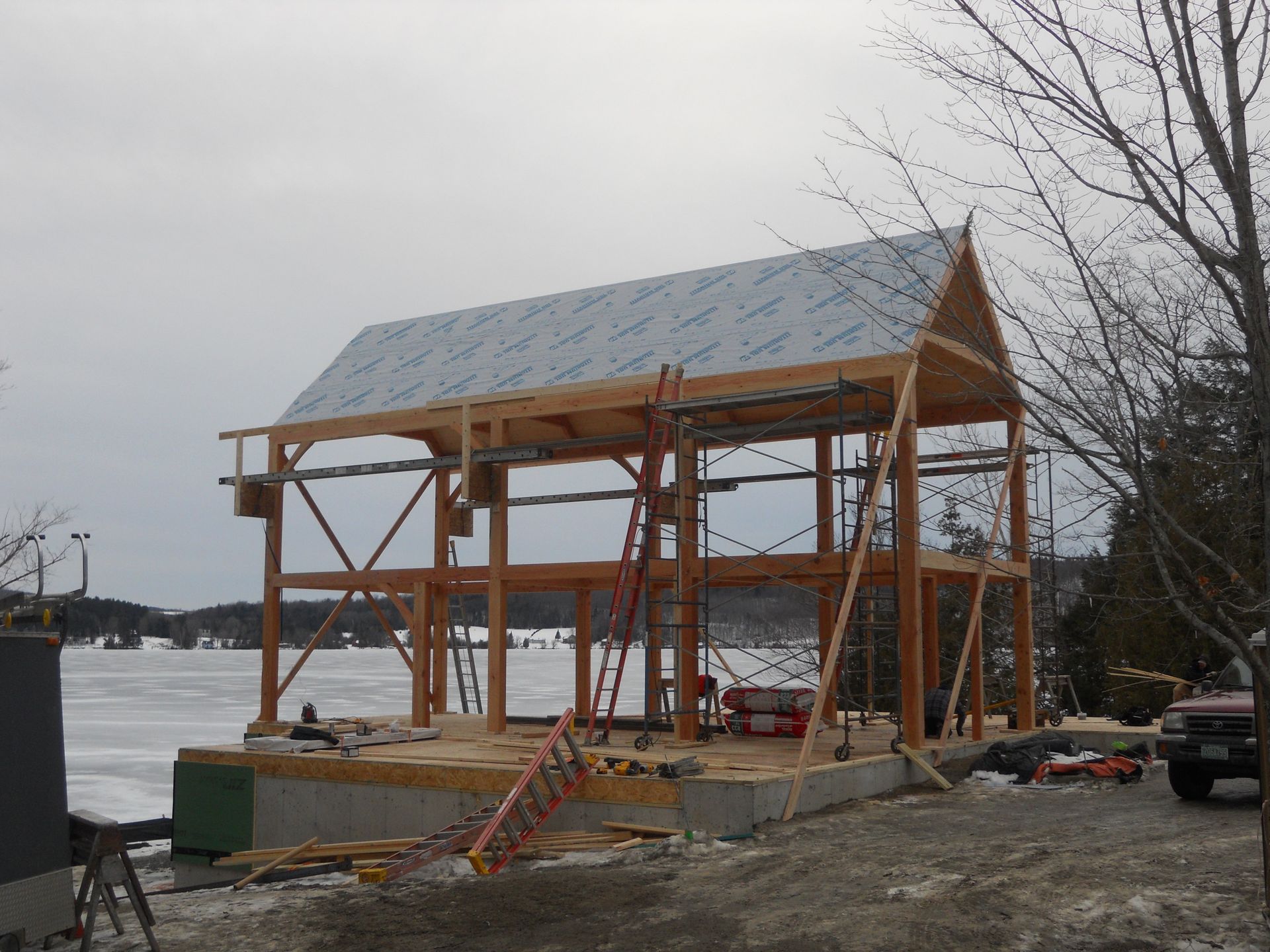 A large wooden structure is being built in the middle of a snowy field