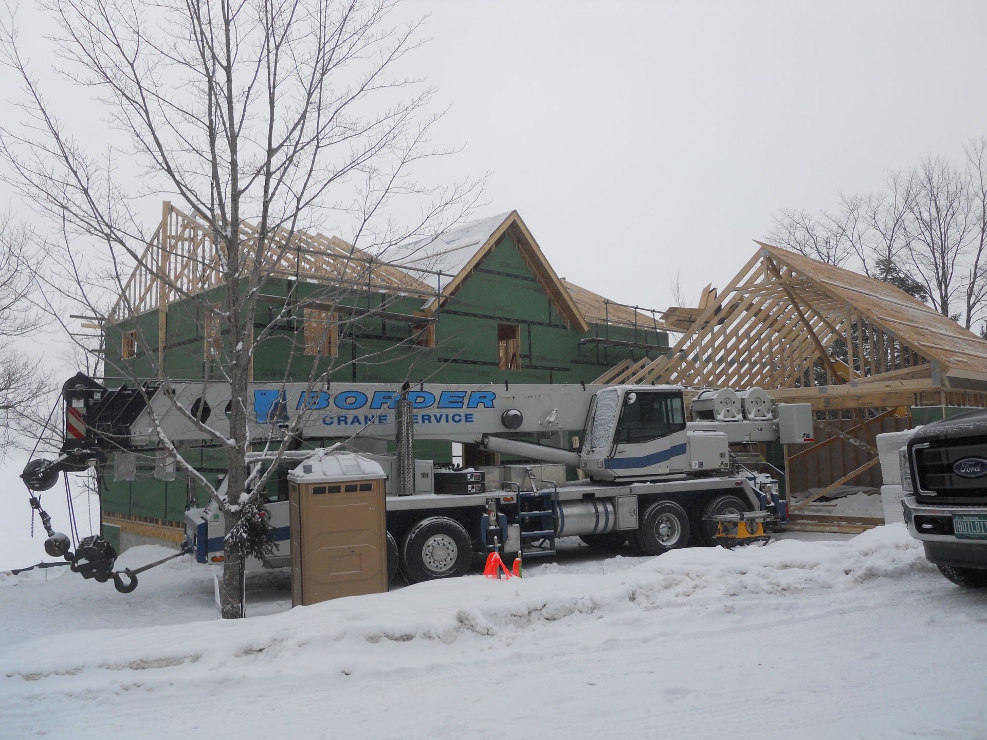 A crane is parked in front of a house under construction