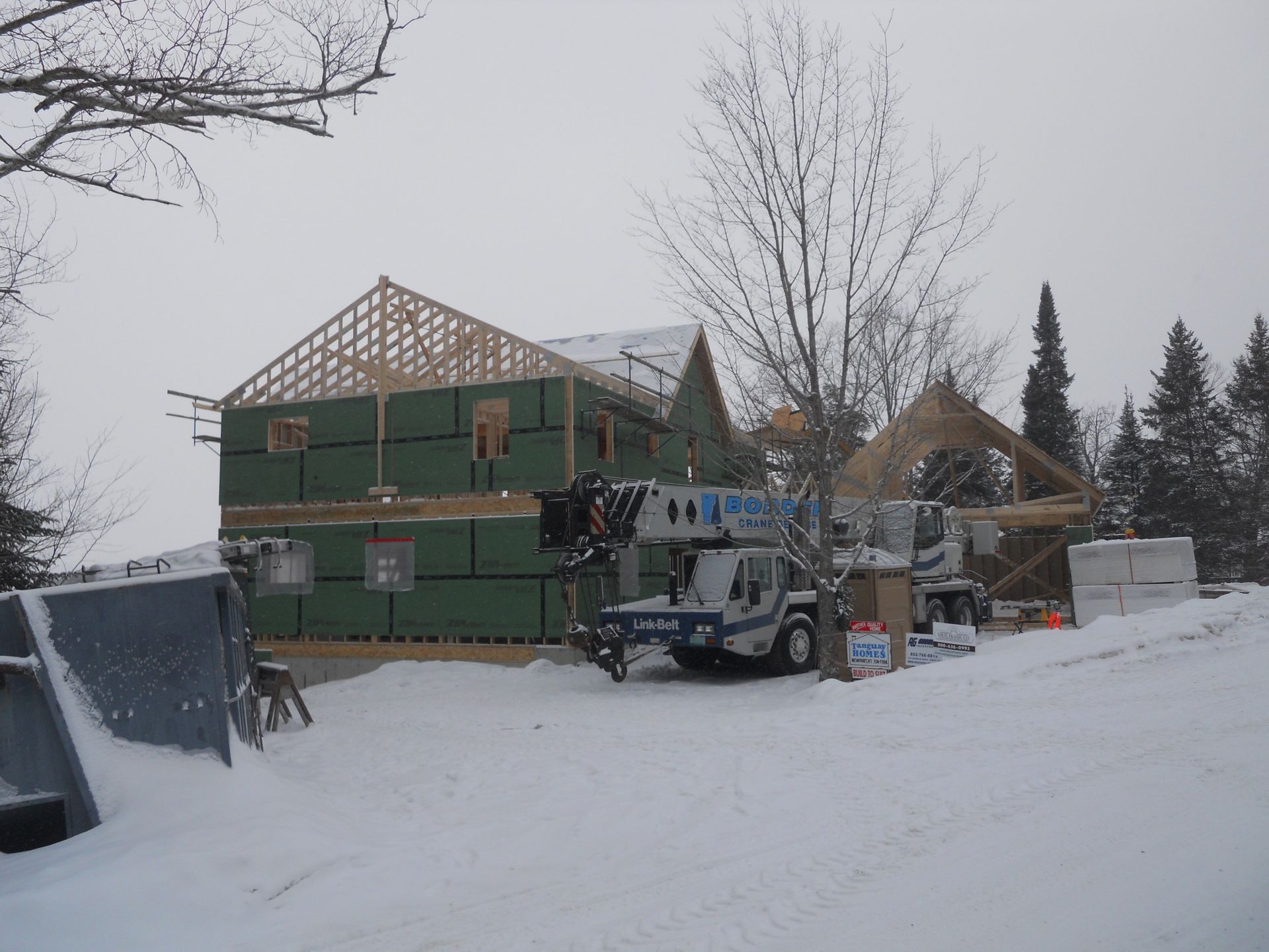 A crane with the number 14 on it is parked in front of a house under construction