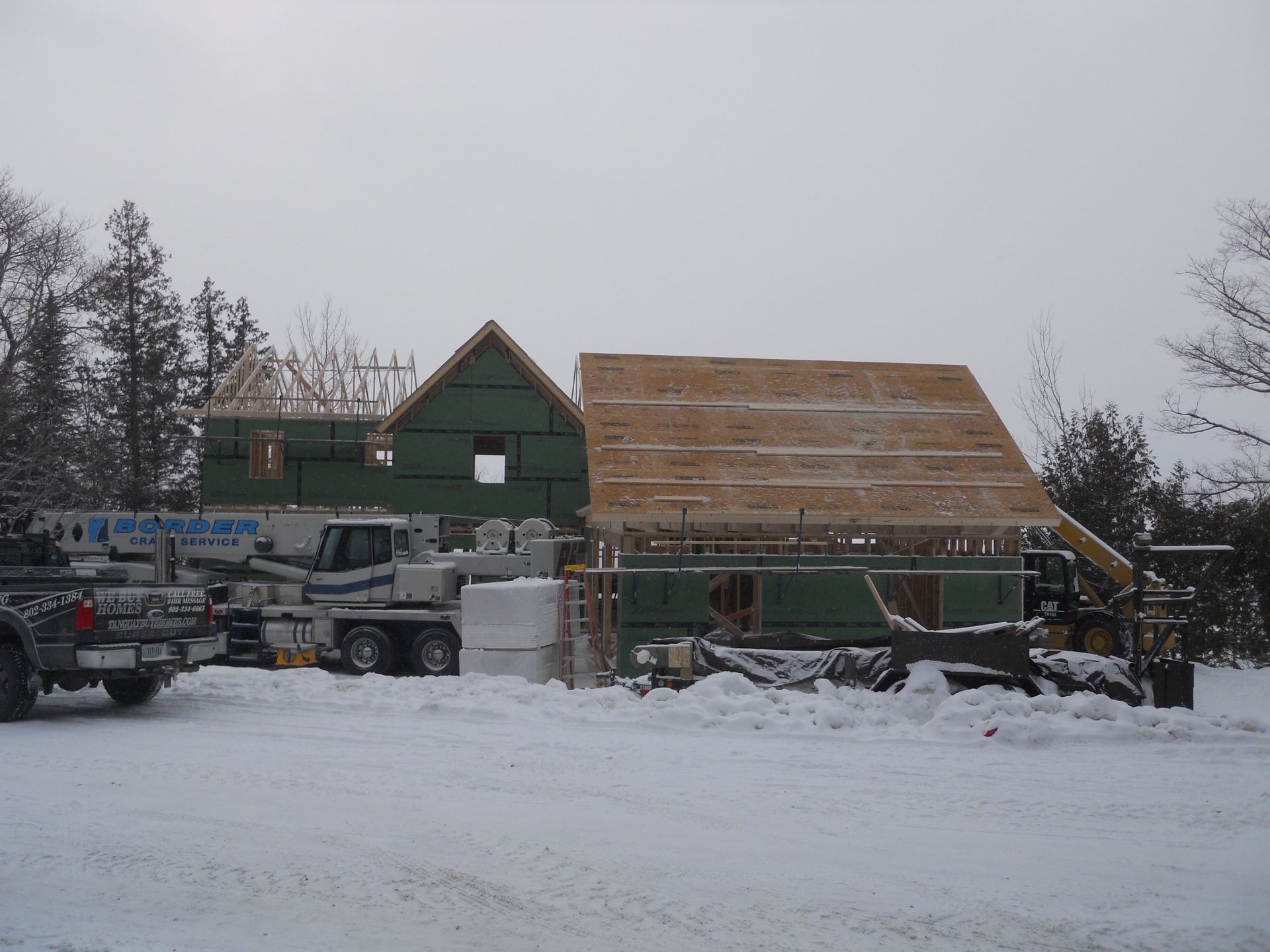 A truck is parked in the snow in front of a house under construction