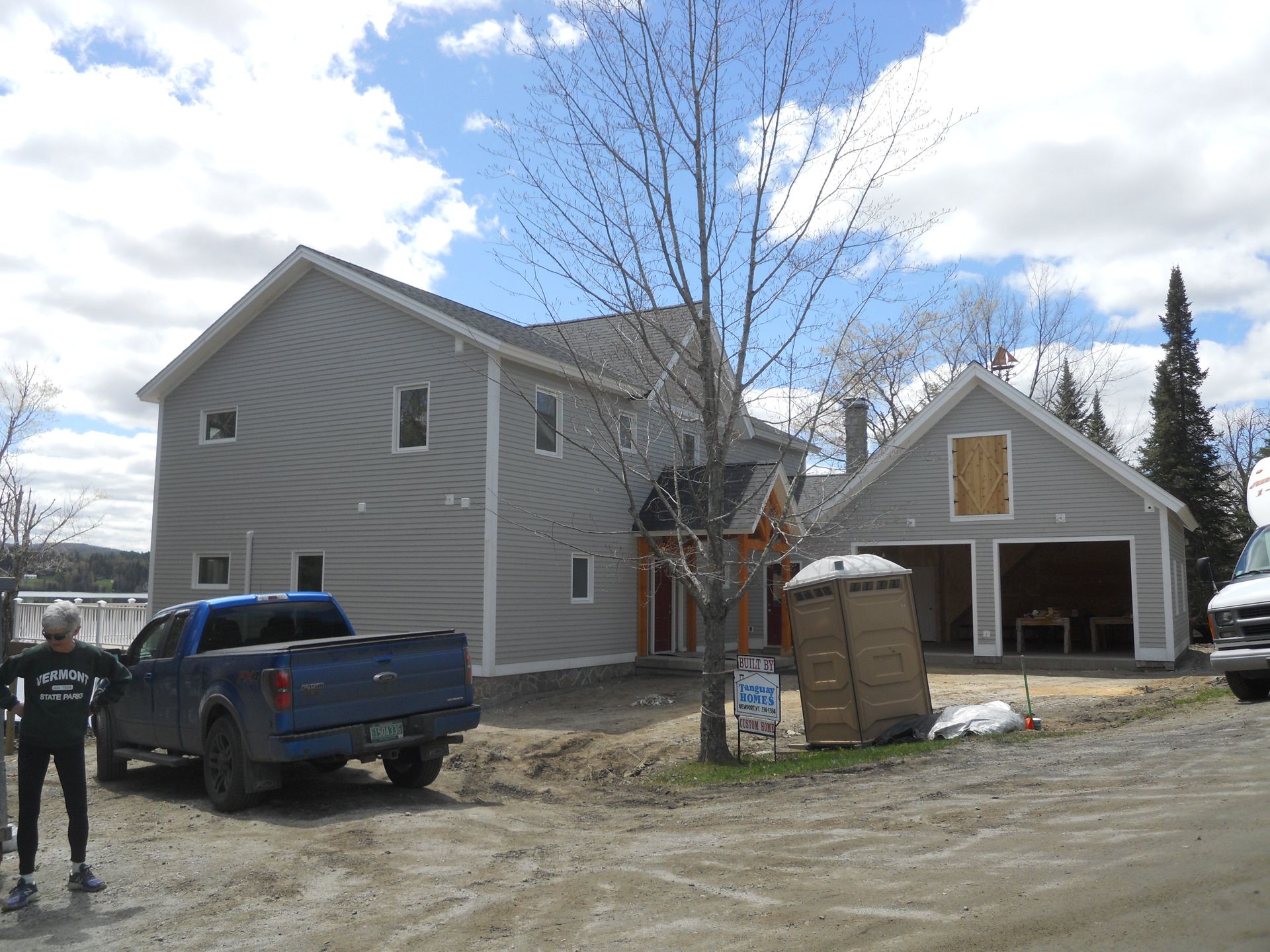 A blue truck is parked in front of a house that is under construction