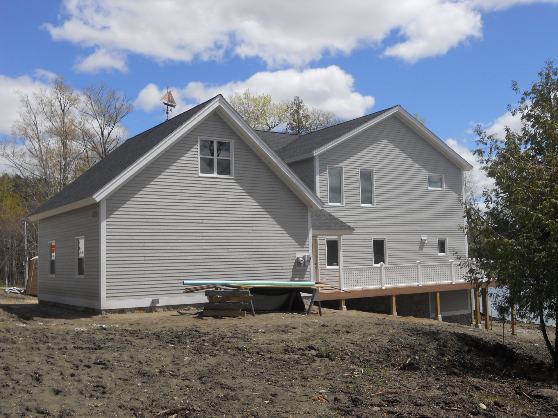 A large white house sits on top of a dirt hill