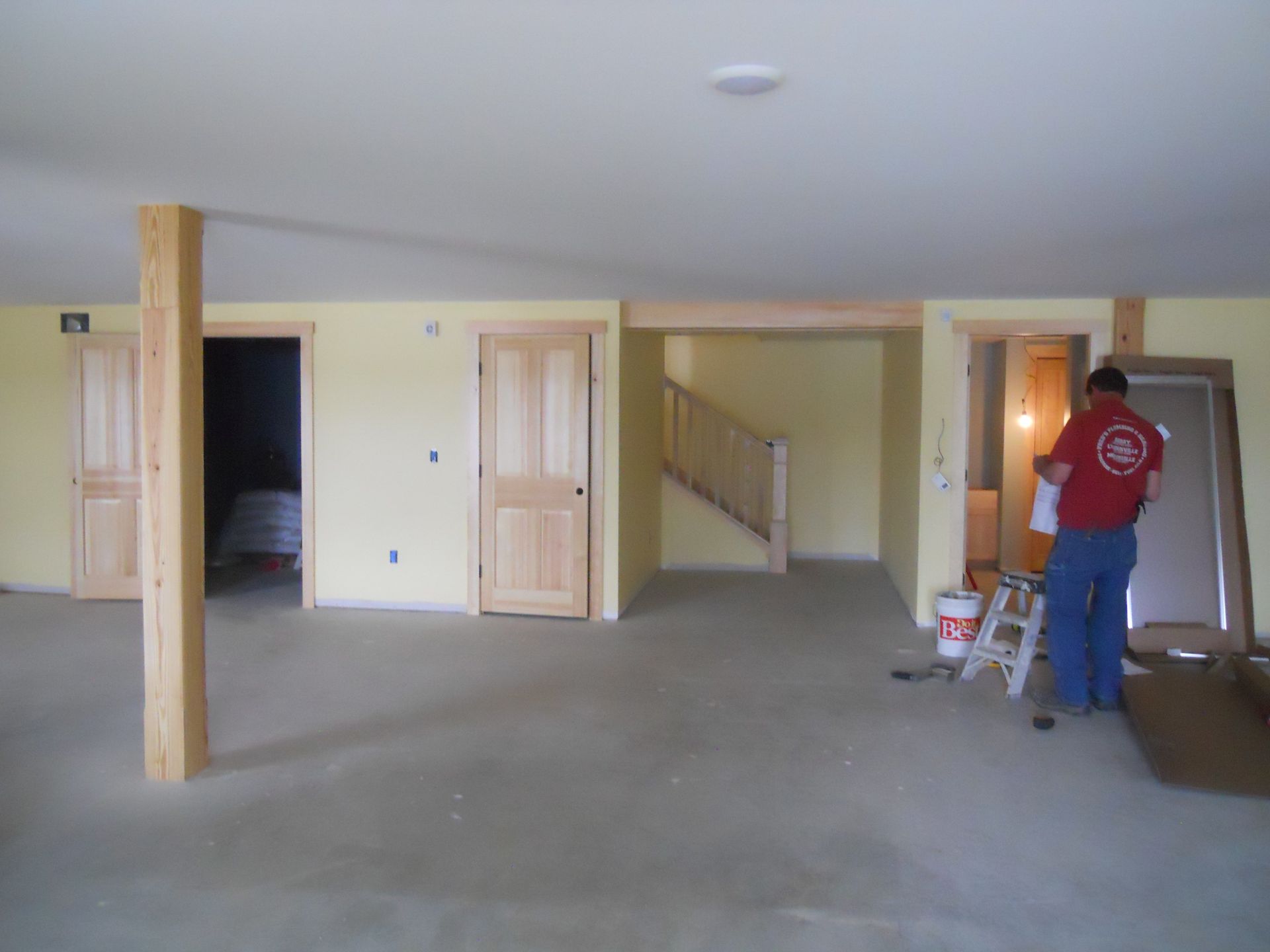 A man standing in an empty room with a red shirt that says ' aa ' on it