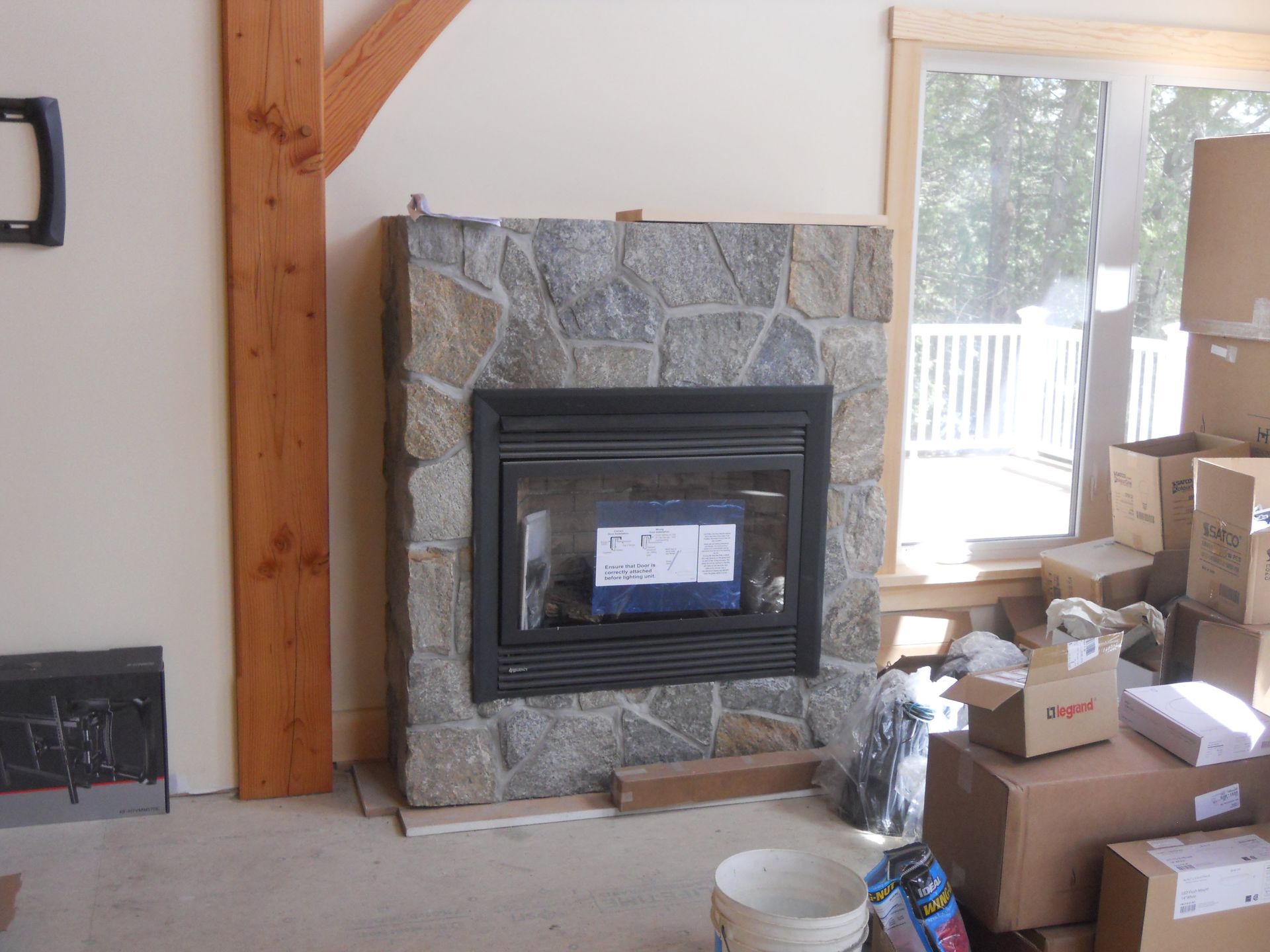 A stone fireplace in a living room with boxes around it