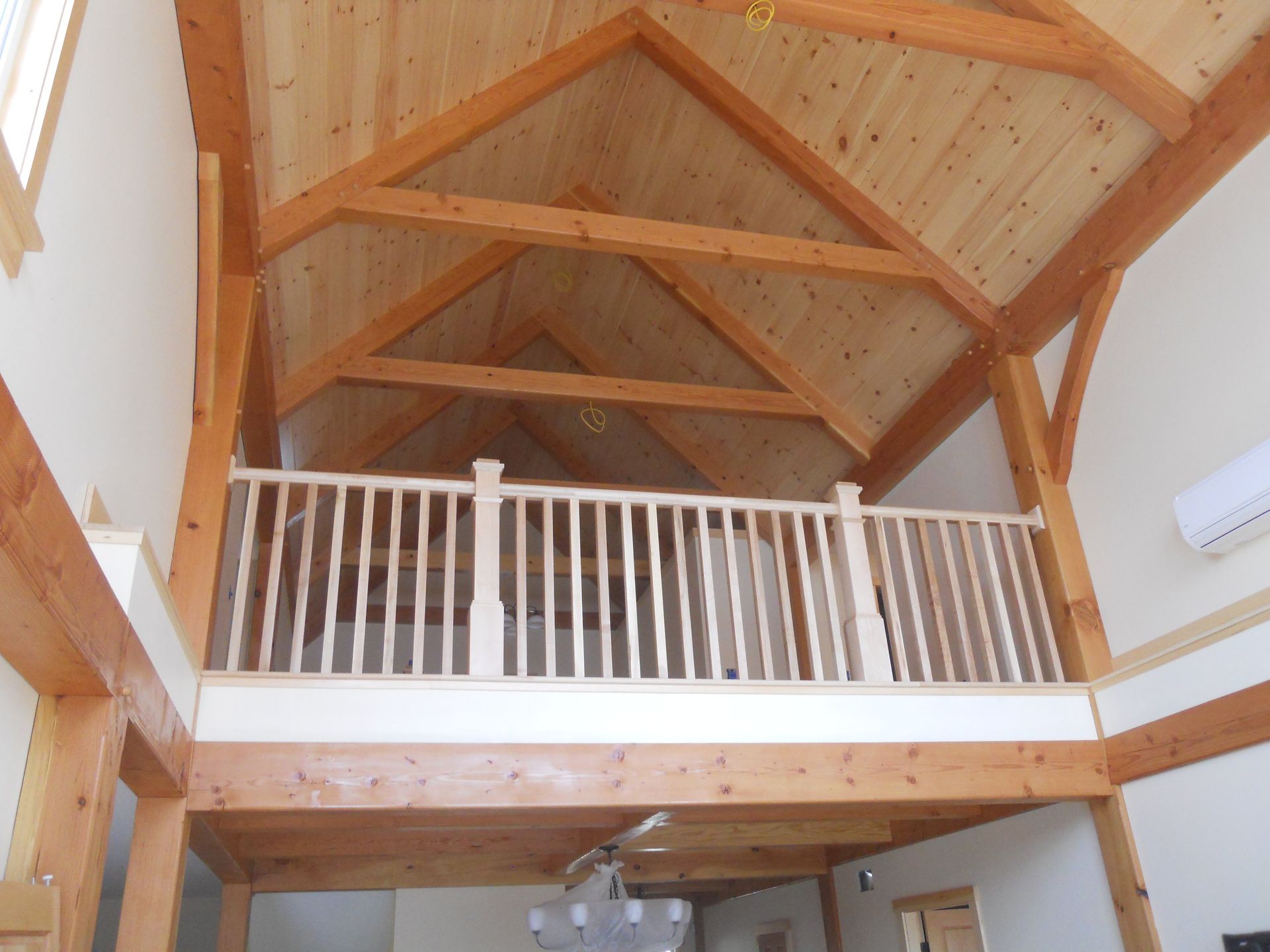 A wooden balcony with a white railing and a vaulted ceiling