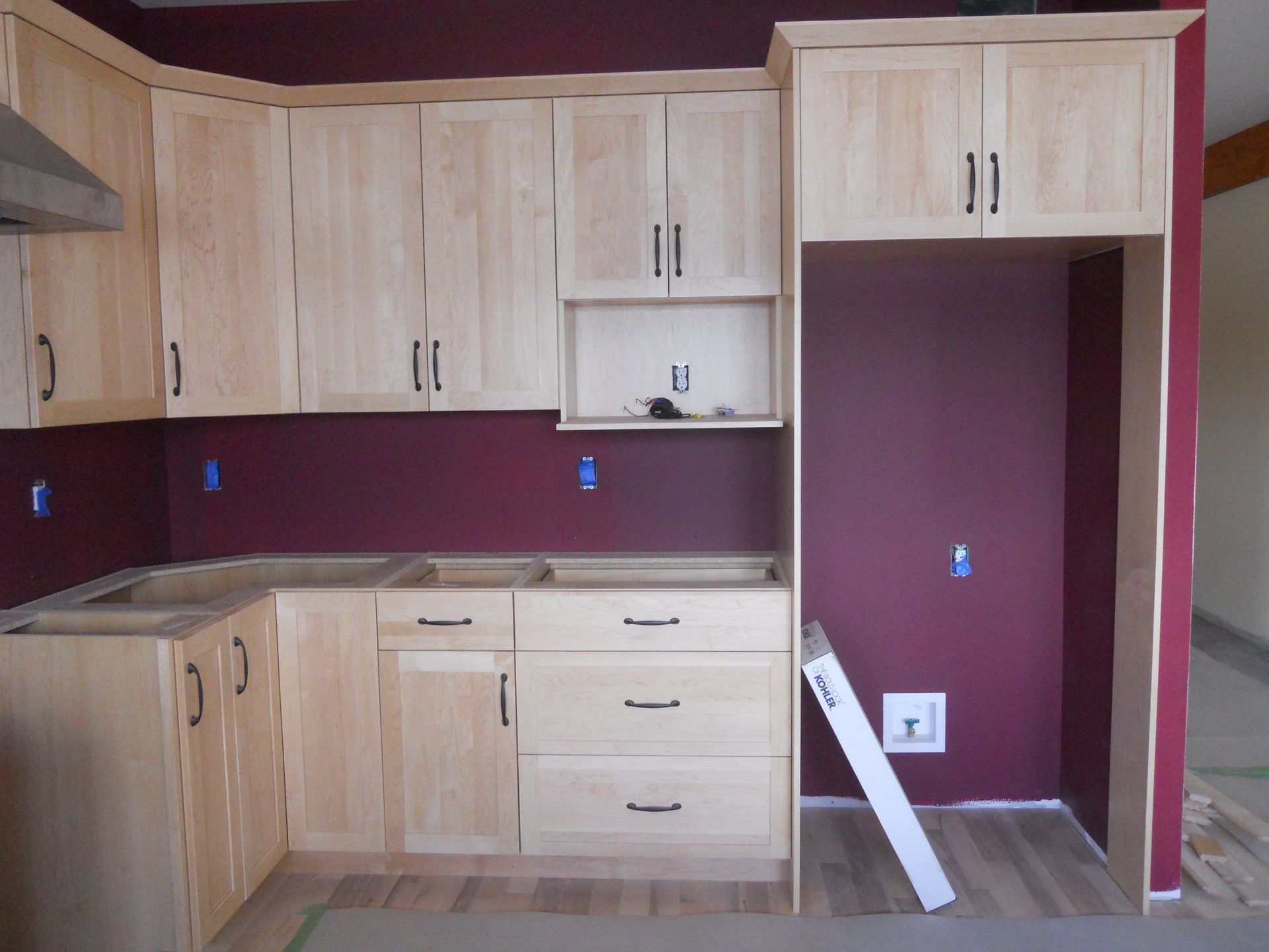 A kitchen with wooden cabinets and a red wall
