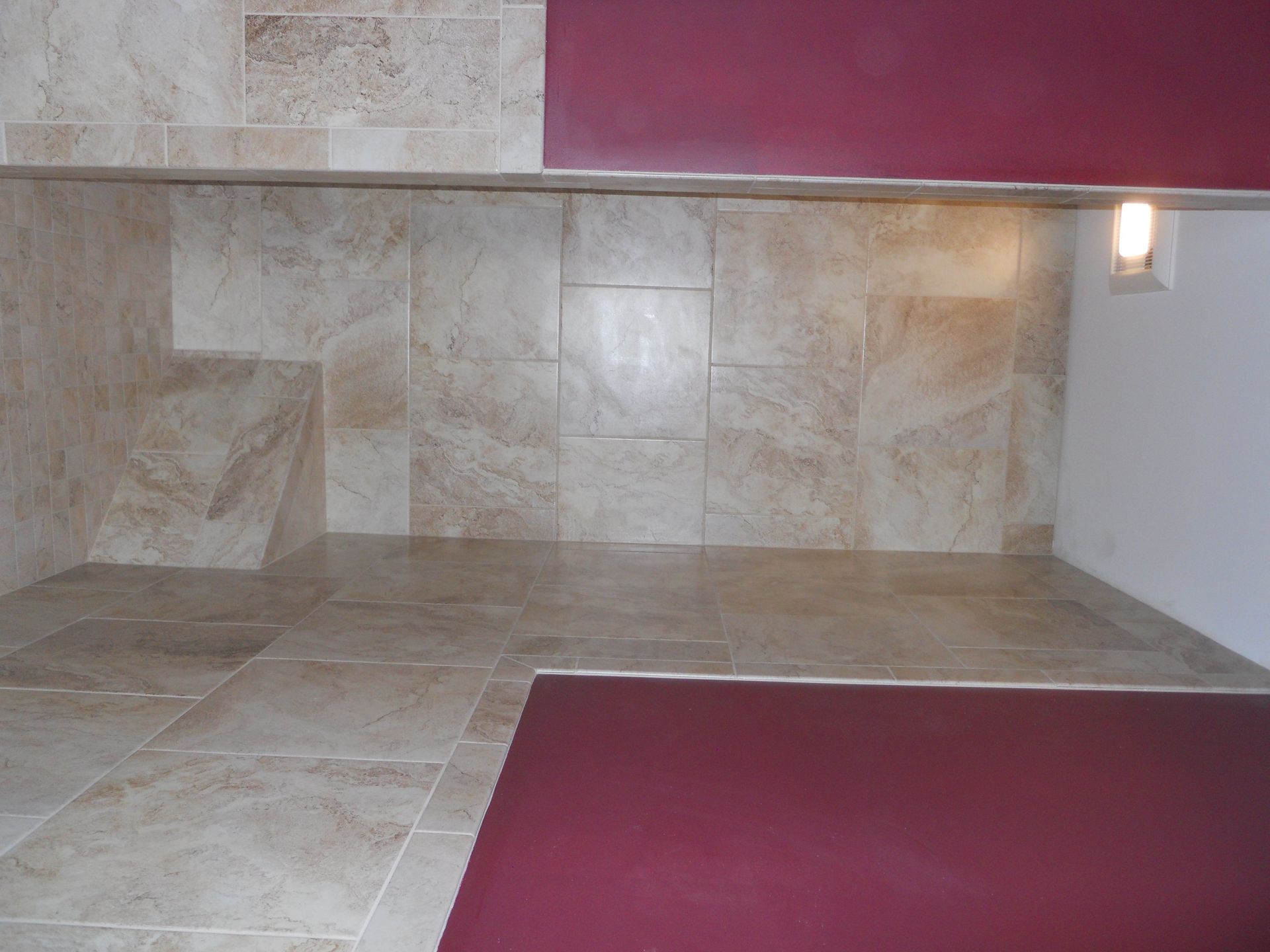 A corner of a room with tiles and a red rug