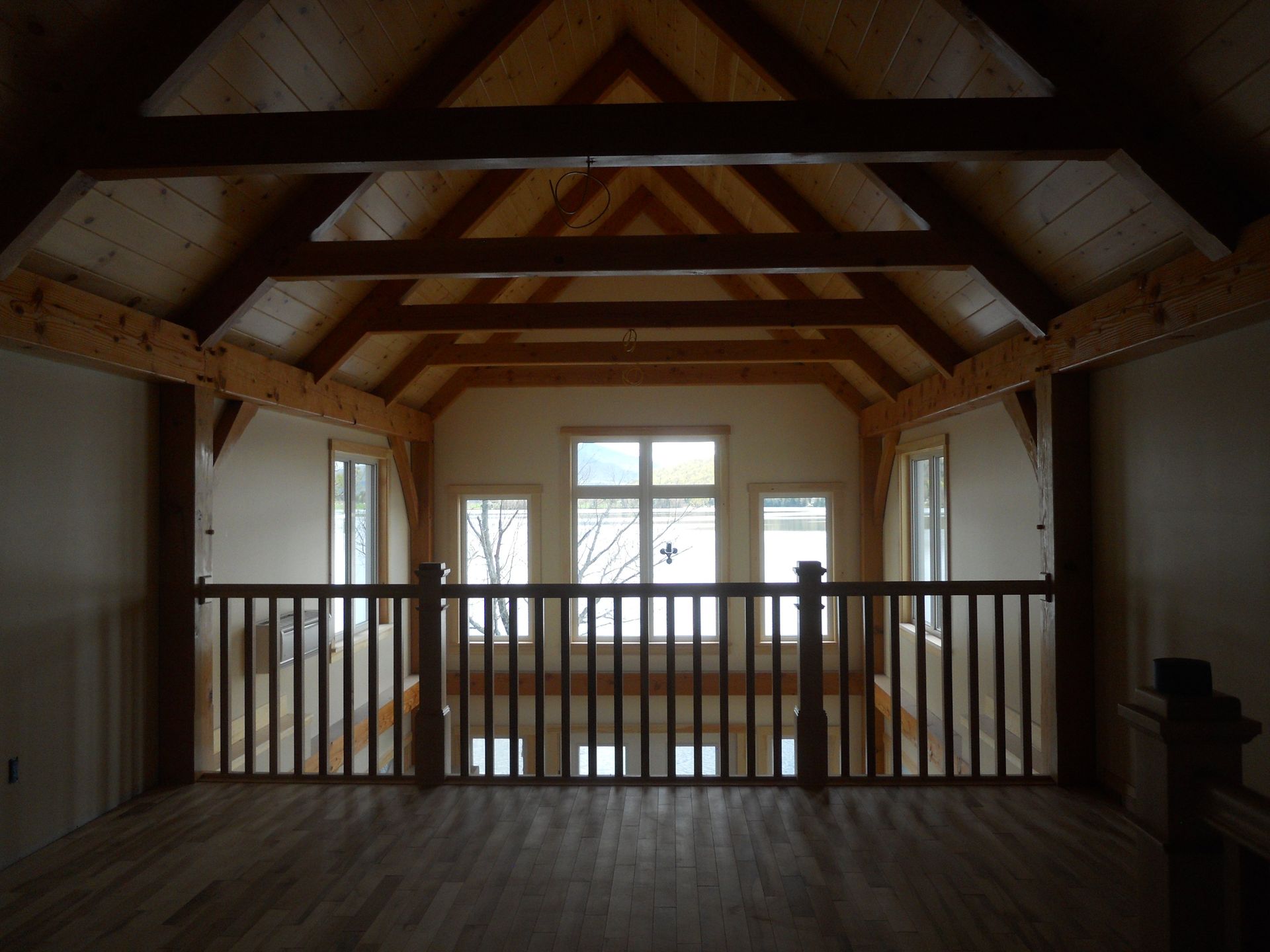 An empty room with a wooden railing and a vaulted ceiling
