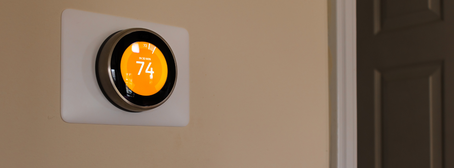 A smart thermostat is hanging on a wall next to a door in a Vermont home.