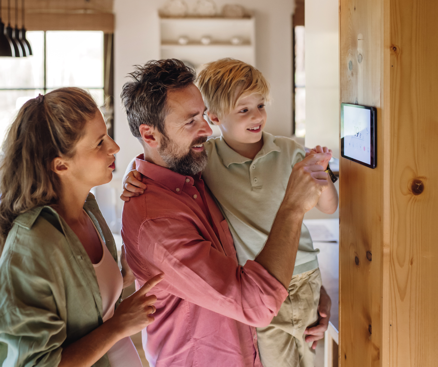 A family is looking at a smart thermostat in a living room in a home in Vermont.