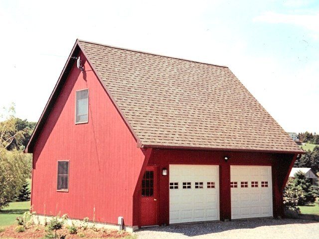 A red barn with white garage doors and a brown roof