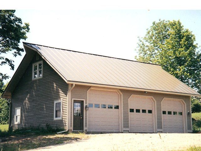 A house with three garage doors and a metal roof