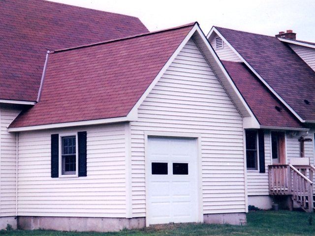A white house with a red roof and a white garage door