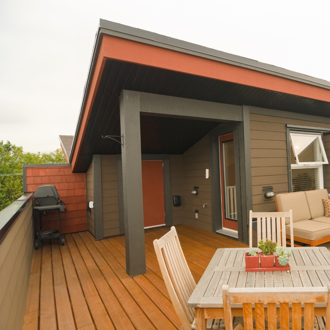 Rooftop deck with table, chairs, barbecue and additional outdoor seating.