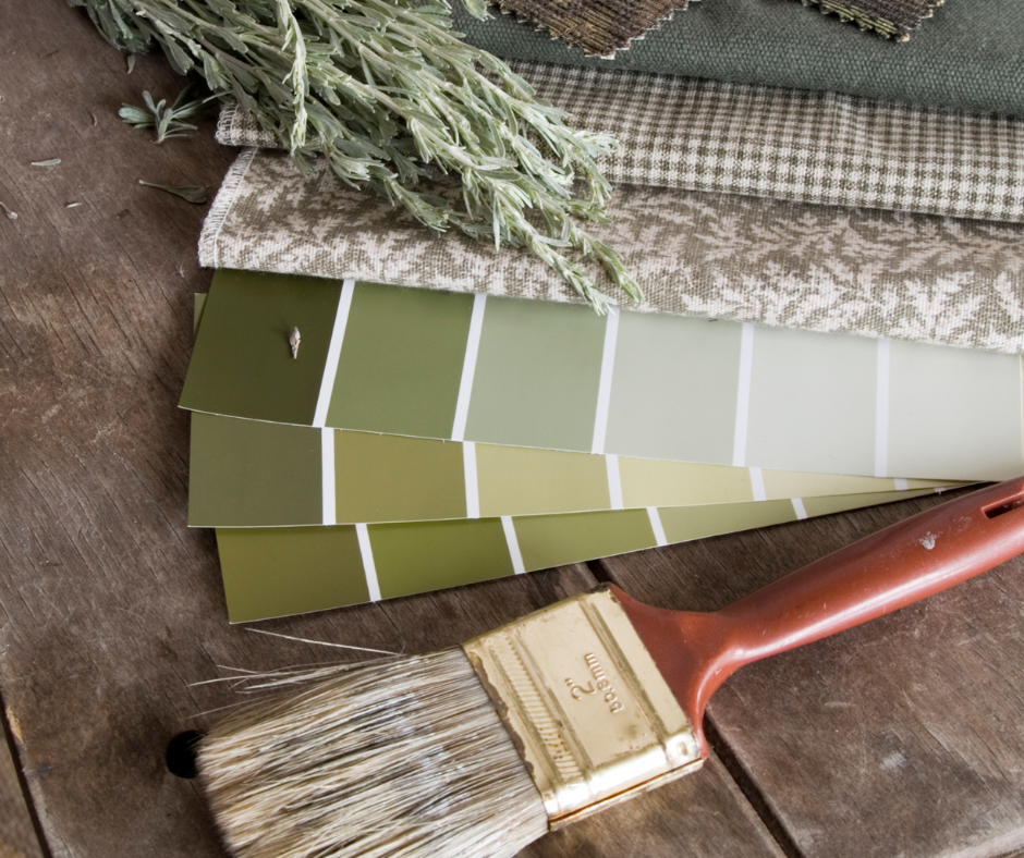 A paint brush is sitting on a wooden table next to a stack of paint samples