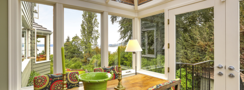 A sunroom with a dining table and chairs looking out at a Vermont landscape