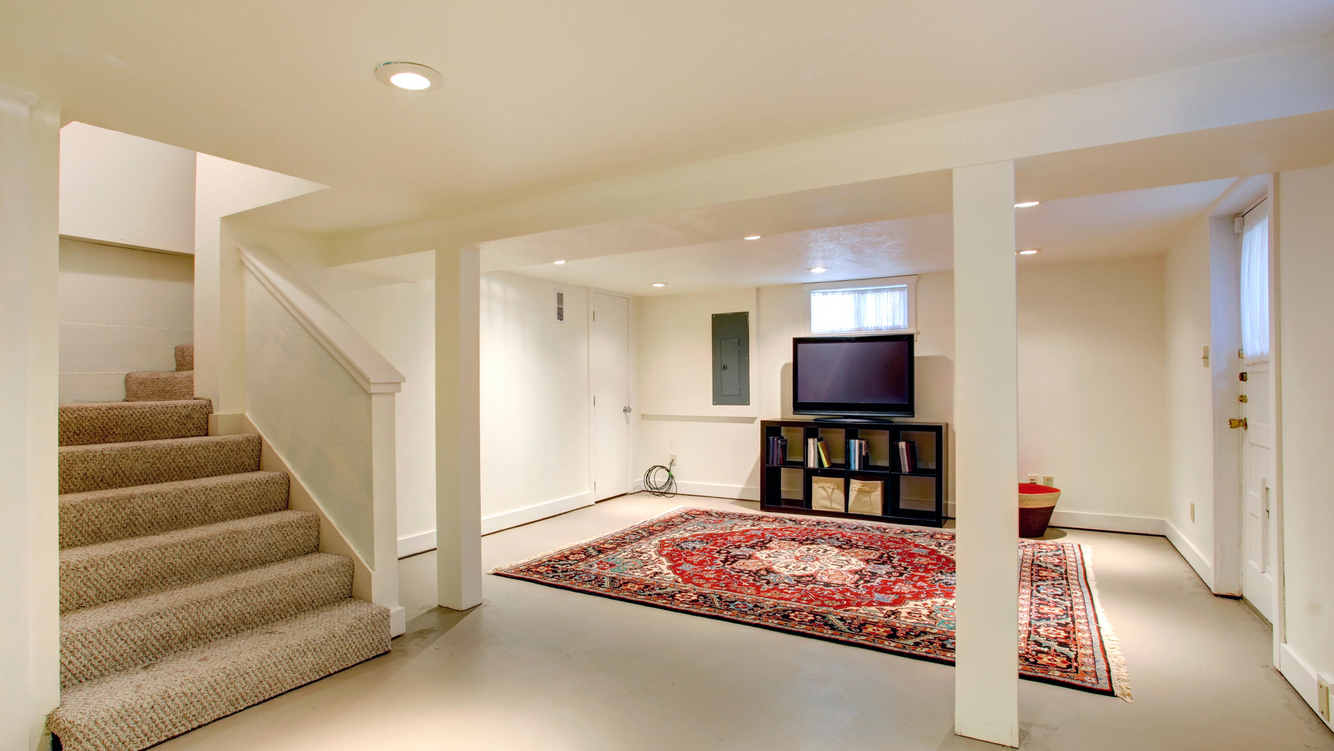 A finished basement with stairs and a flat screen TV 