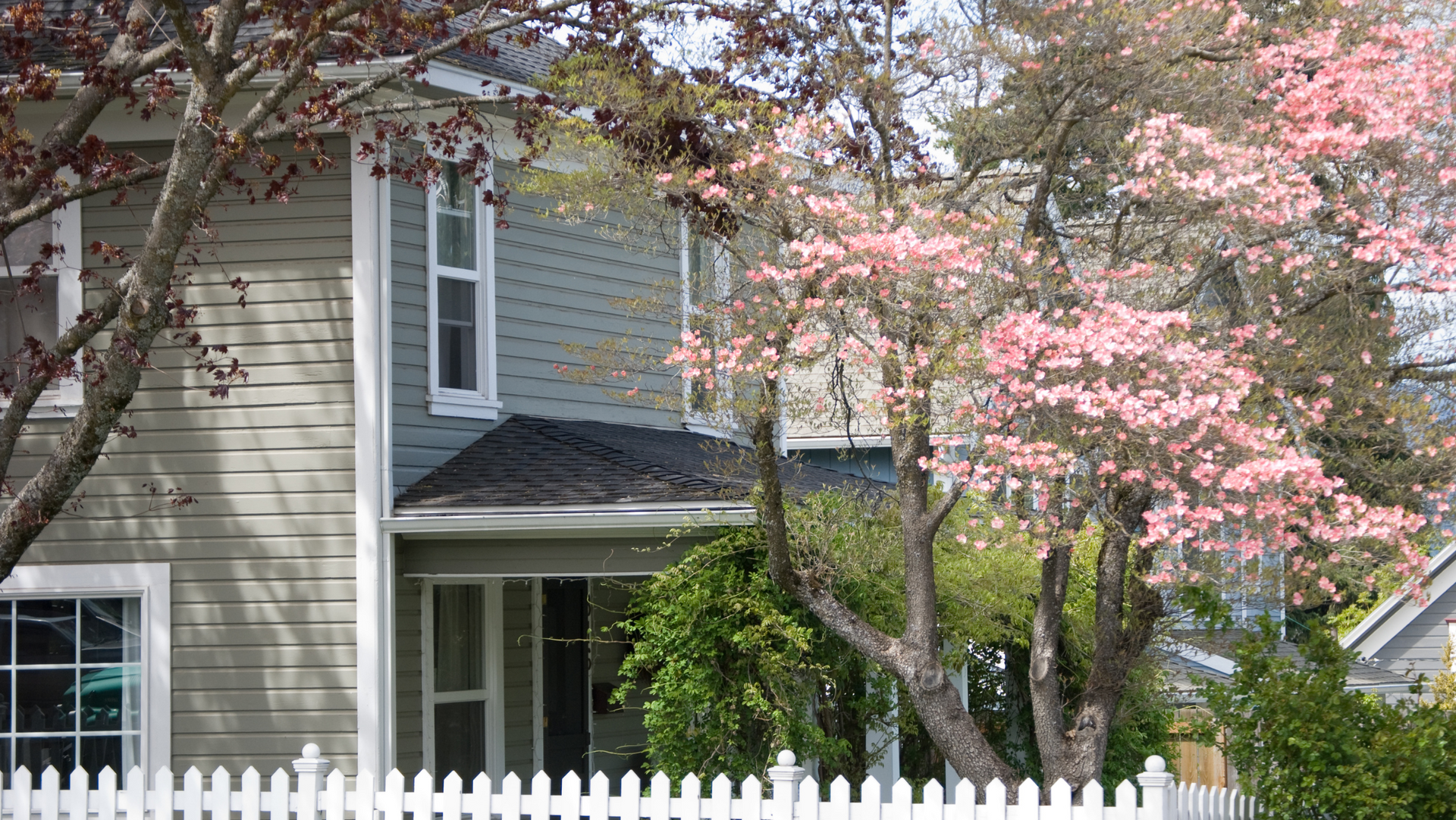 A house in Vermont with a white picket fence and pink flowers