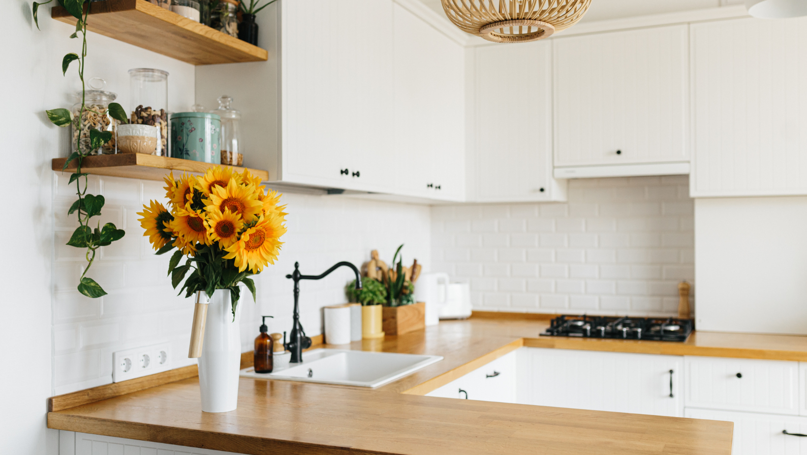 Kitchen with white cabinets, butcher block countertops, and a bouquet of sunflowers.