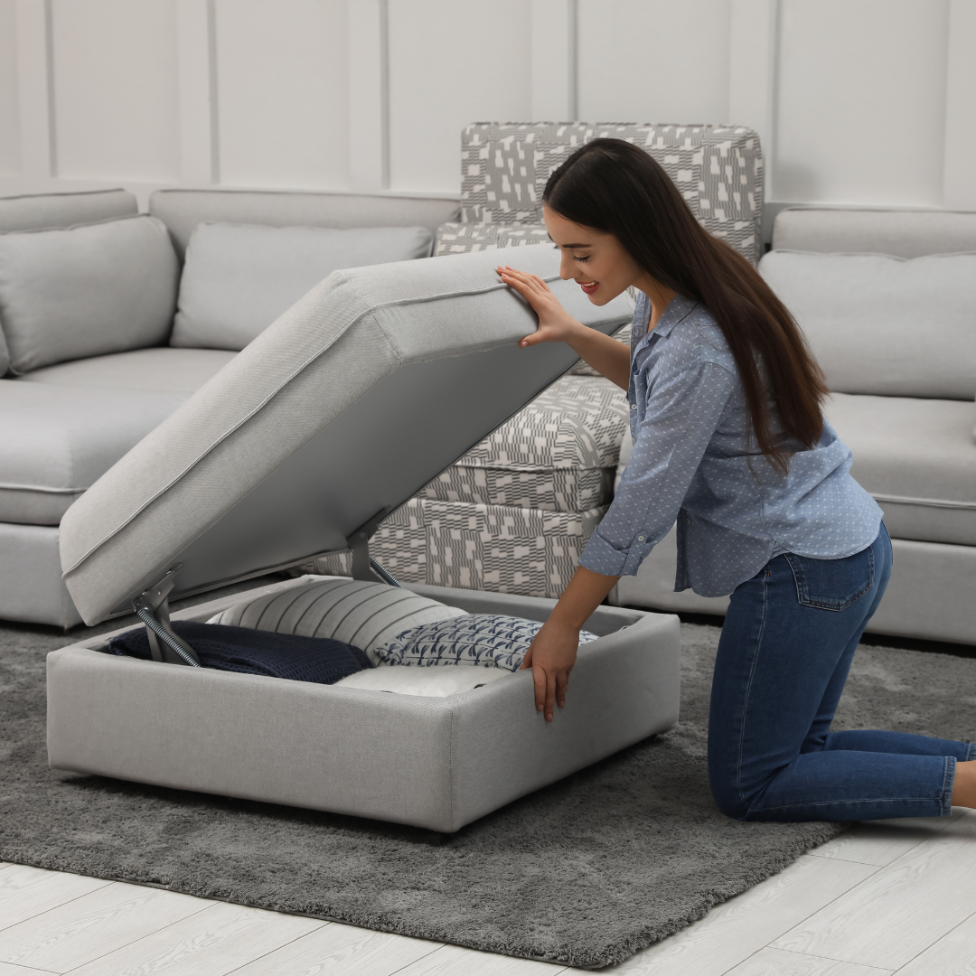 A woman utilizing her multi-functional couch with an ottoman with a storage section. 