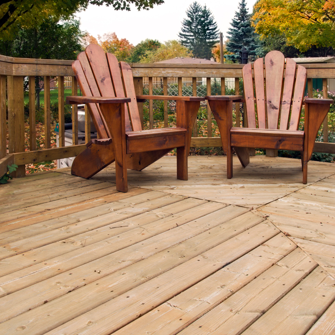 Wooden outdoor deck with two Adirondack chairs on it.