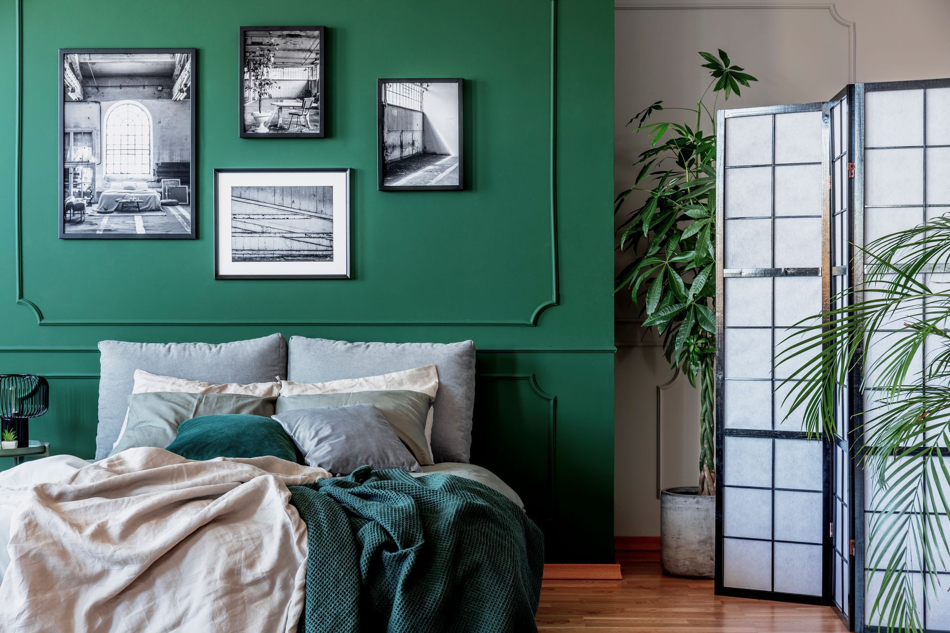 A gallery of black and white photos on an emerald green bedroom wall