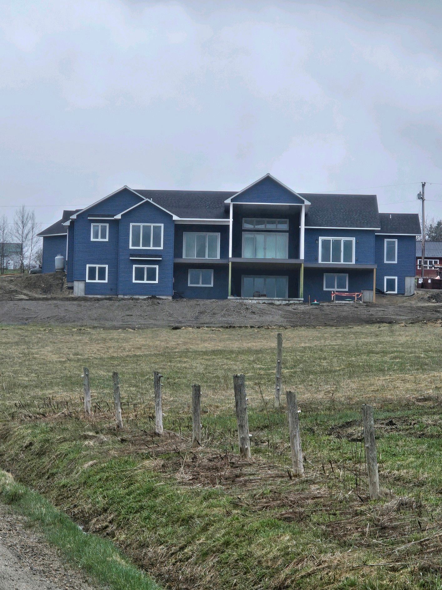 A large blue house in Vermont that sits in the middle of a grassy field