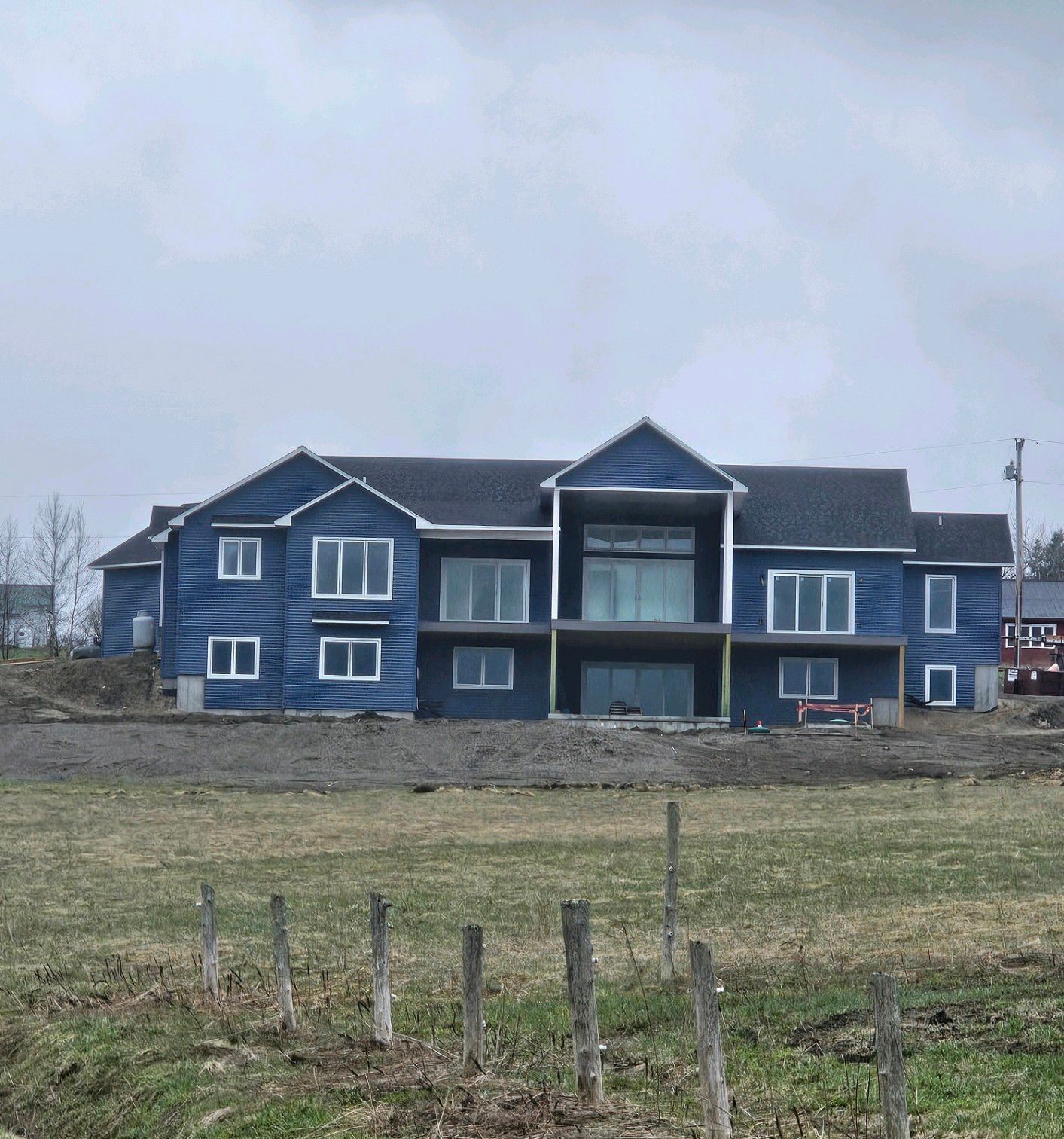 A large blue house sits in the middle of a grassy field