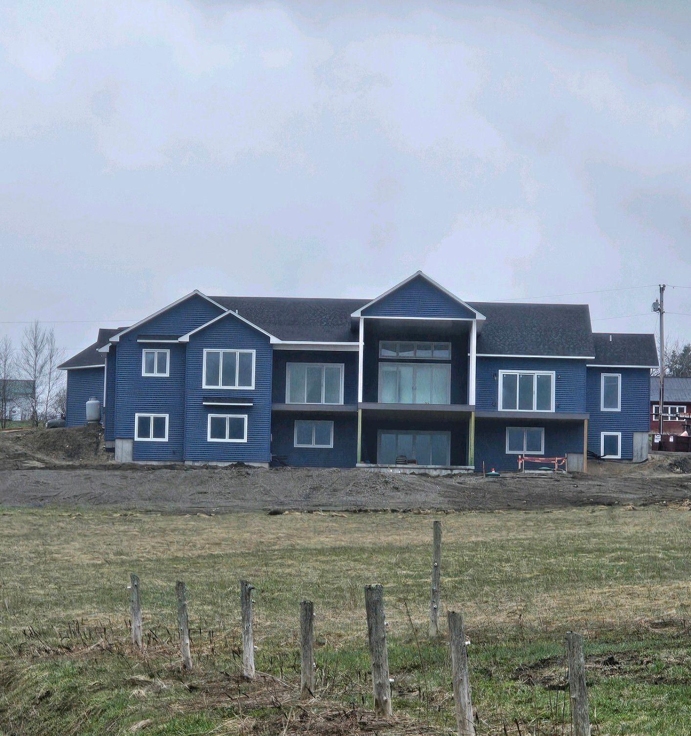 A large blue house sits in the middle of a grassy field