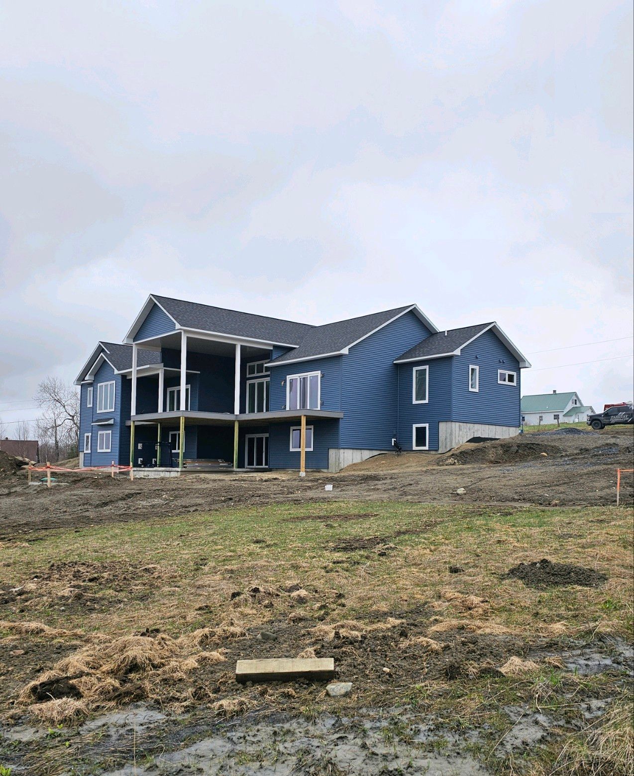 A large blue house is being built on top of a dirt hill.