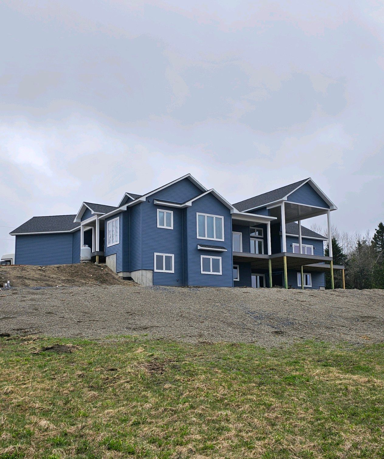 A large blue house is sitting on top of a grassy hill.