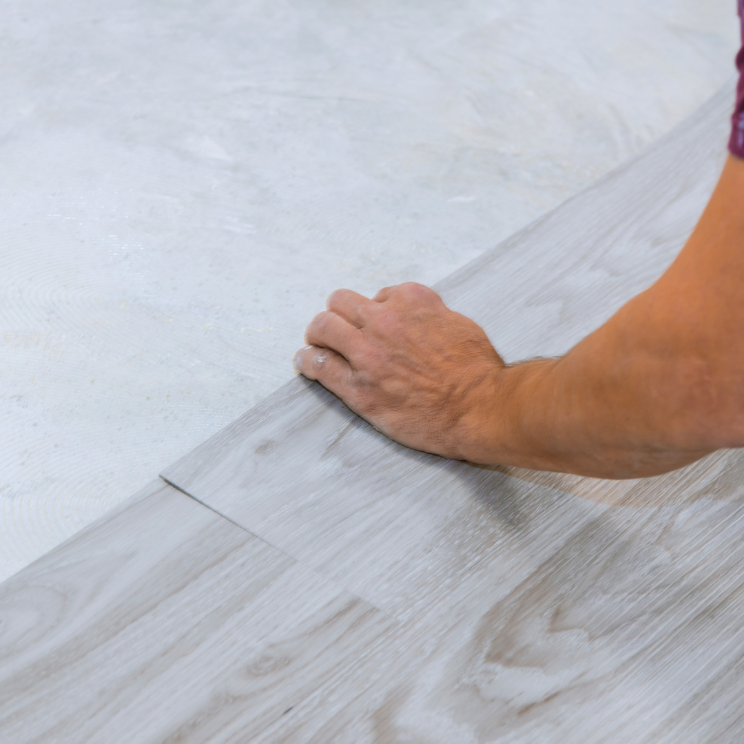 Contractor installing grey wood laminate flooring.