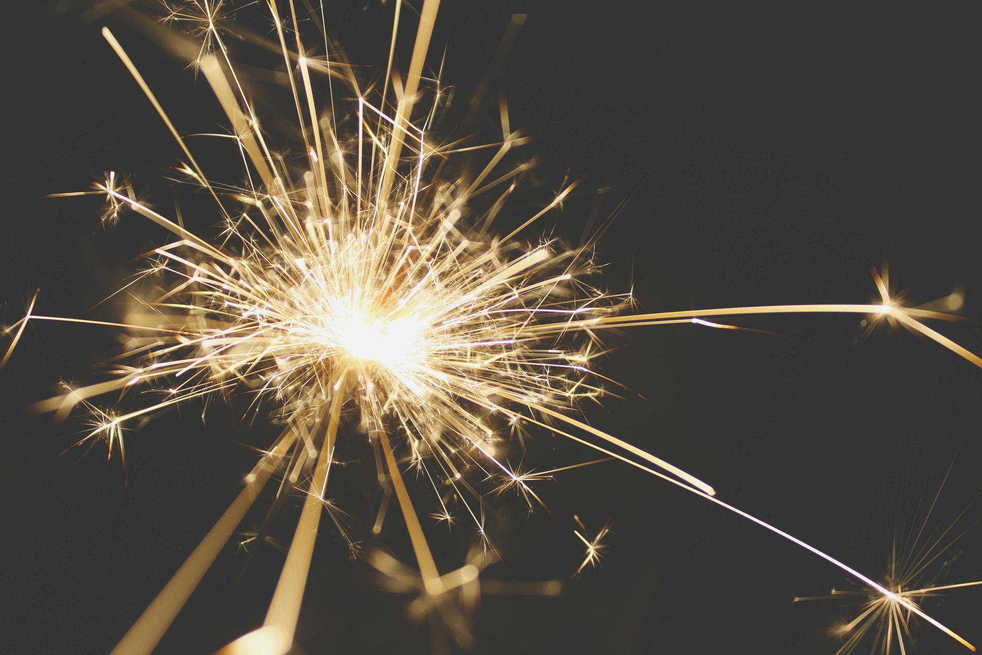 A sparkler that is lit in a dark room celebrating New Years Eve