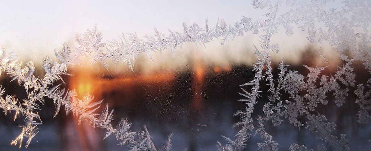 A frozen window with a sunset in the background