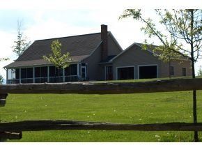 A house with a screened in porch is behind a wooden fence