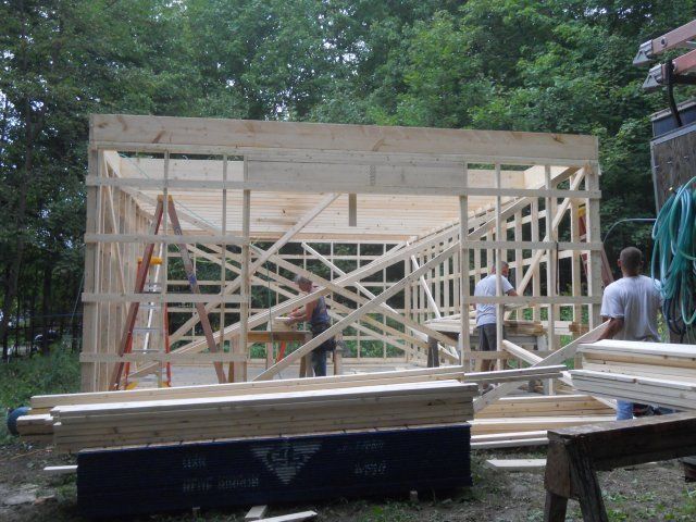 A wooden structure is being built with a ladder in the background